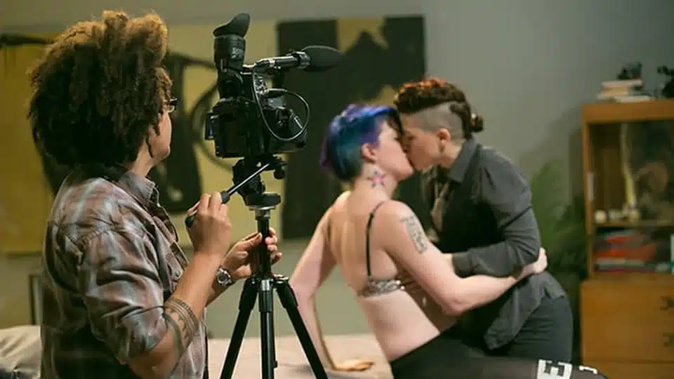 Una regista filma due persone che si baciano, dietro le quinte di un set Pink & White